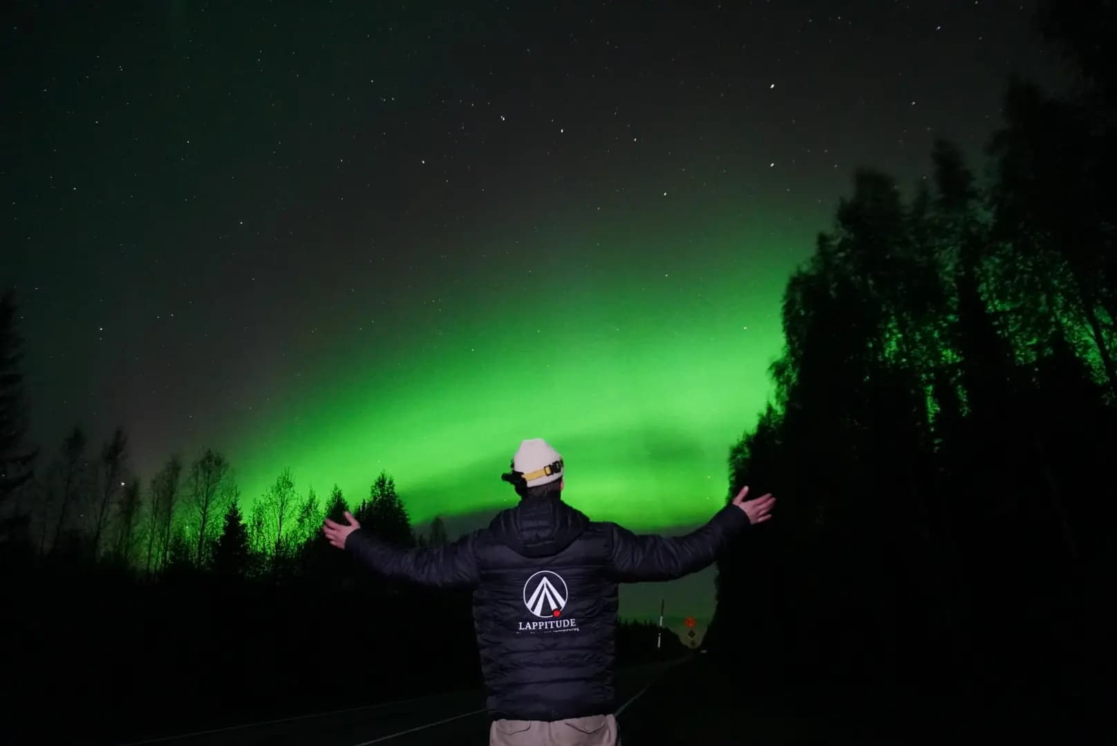 a guy with a jacket with lappitude logo in front of northern lights